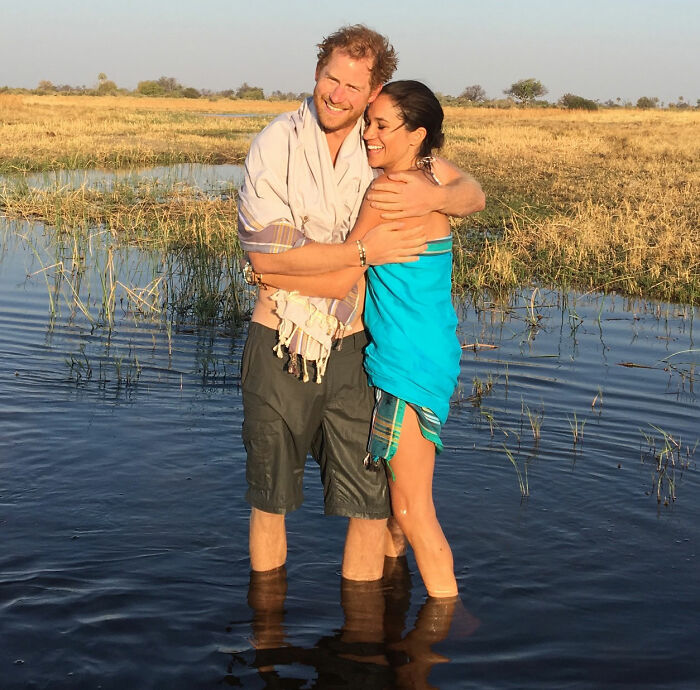 Prince Harry and Meghan Markle embracing while standing in water during outdoor adventure, highlighting Meghan Markle throwback post.