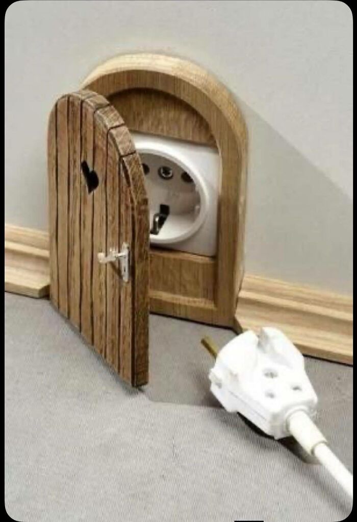 Woodworking project featuring a small wooden door cleverly hiding an electrical outlet with a heart-shaped cutout.