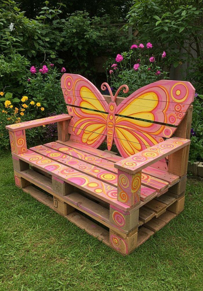 Colorful butterfly-themed wooden bench in garden showcasing beautifully crafted woodworking projects with intricate painted details.