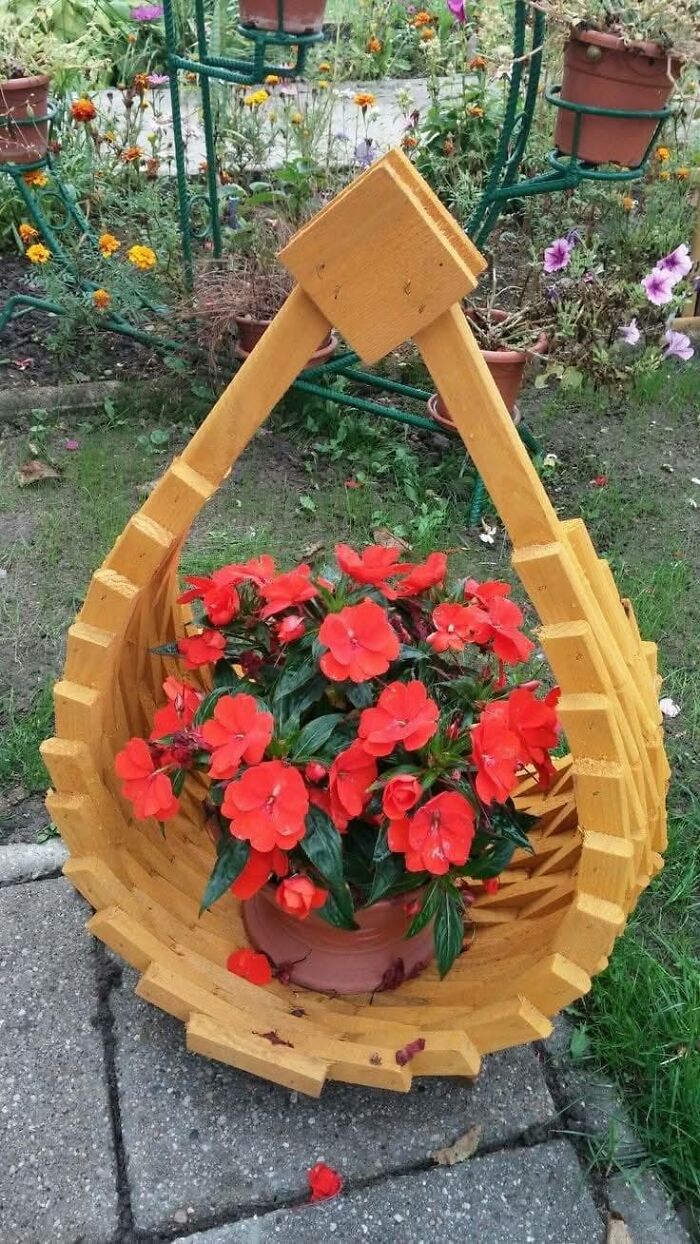 Wooden basket woodworking project holding vibrant red flowers in a garden setting showcasing impressive craftsmanship.