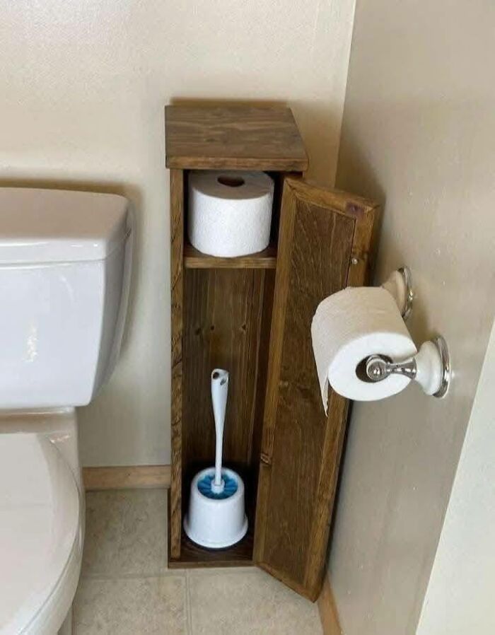 Woodworking project showing a tall wooden bathroom storage cabinet holding toilet brush and extra toilet paper rolls.