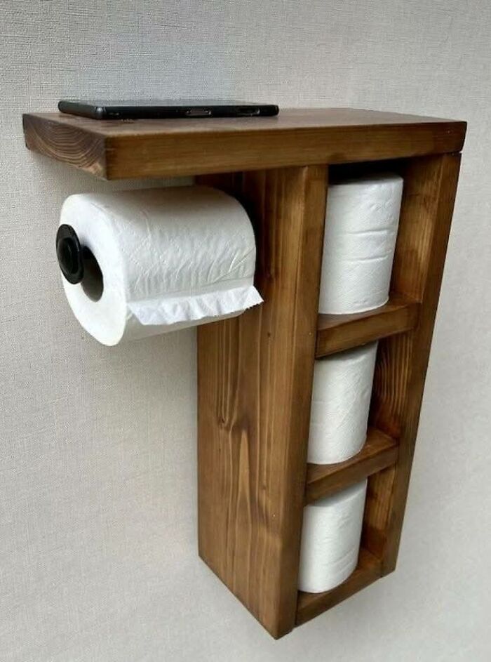 Wall-mounted woodworking project holding toilet paper rolls with a shelf for small items, showcasing beautifully crafted woodwork.