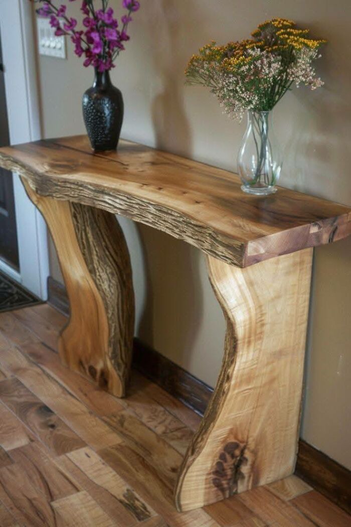 Handcrafted woodworking project of a live edge wooden console table with floral vases on top in a home setting