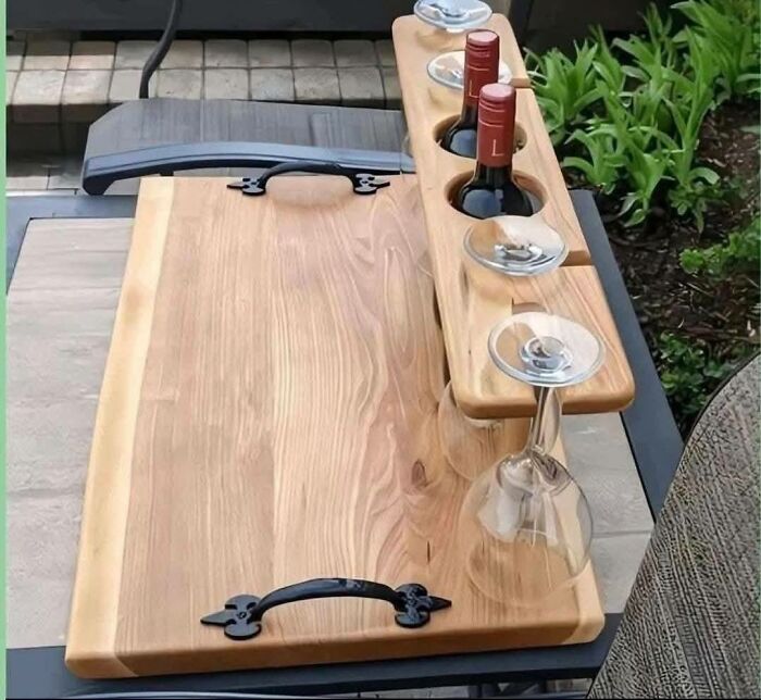 Woodworking project featuring a handcrafted wooden wine and glass holder with metal handles on a patio table.