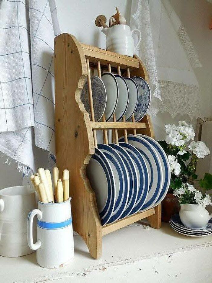 Wooden plate rack woodworking project holding blue and white plates, displayed in a cozy kitchen setting with flowers.