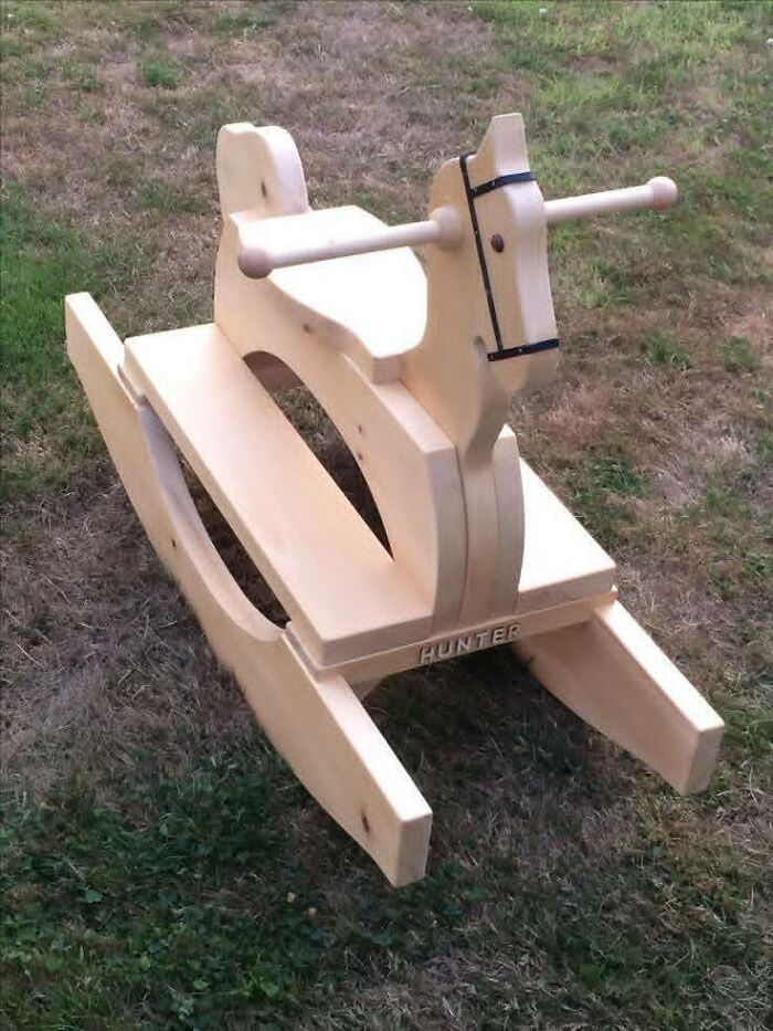 Handcrafted wooden rocking horse with smooth finish, showcasing impressive woodworking projects on a grassy outdoor surface.