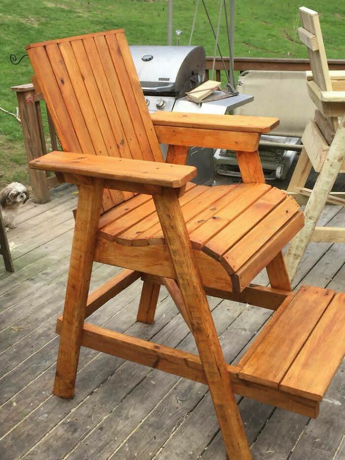 Handcrafted wooden chair with armrests and footrest on a wooden deck, showcasing impressive woodworking projects outdoors.