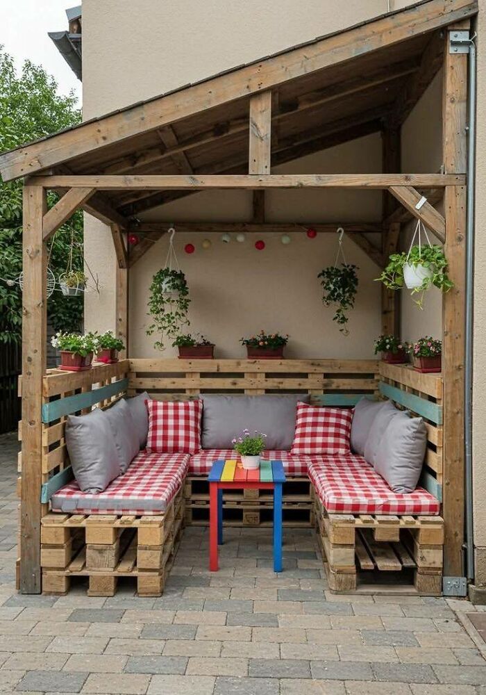 Outdoor seating area with cushioned pallet wood benches and colorful table under a wooden pergola woodworking project.