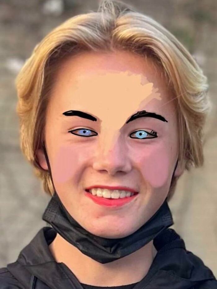 Smiling young person with blonde hair and blue eyes wearing a black jacket and face mask, showing sibling fun moments.