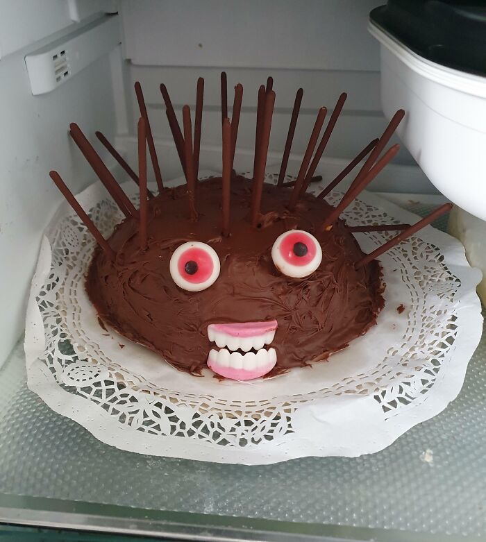 Chocolate cake with candy eyes and teeth, decorated with chocolate sticks, showing fun sibling creativity and bonding moments.