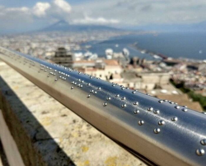 Metal railing with tactile Braille dots installed in a public place, showcasing impressive things countries implemented for accessibility.