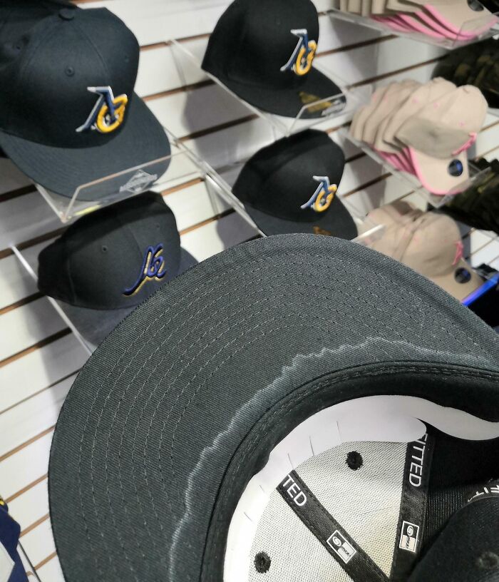 Black fitted caps on display with a stained brim, next-level jerks photo