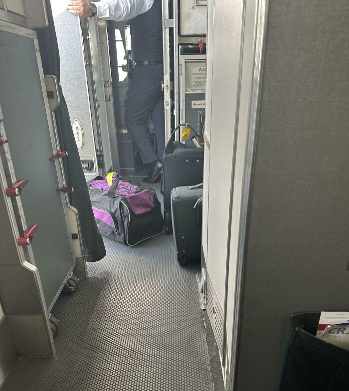 next-level jerks: luggage blocking airplane doorway in galley with crew member standing nearby
