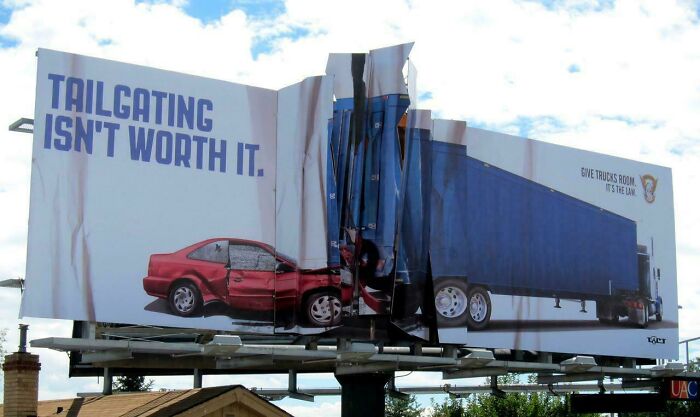 Crumpled print advertisement on a billboard showing a car crashed into a truck, using humor and creativity.