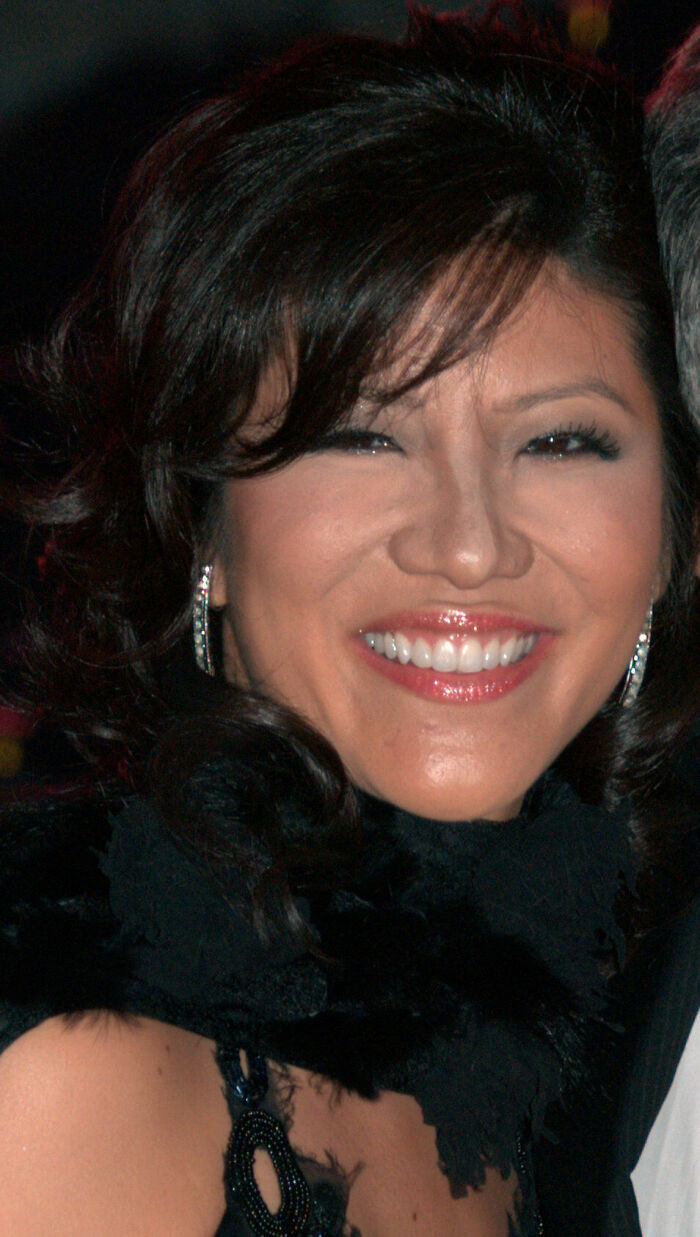 Julie Chen Moonves smiling at a formal event, wearing black attire and earrings with styled dark hair.