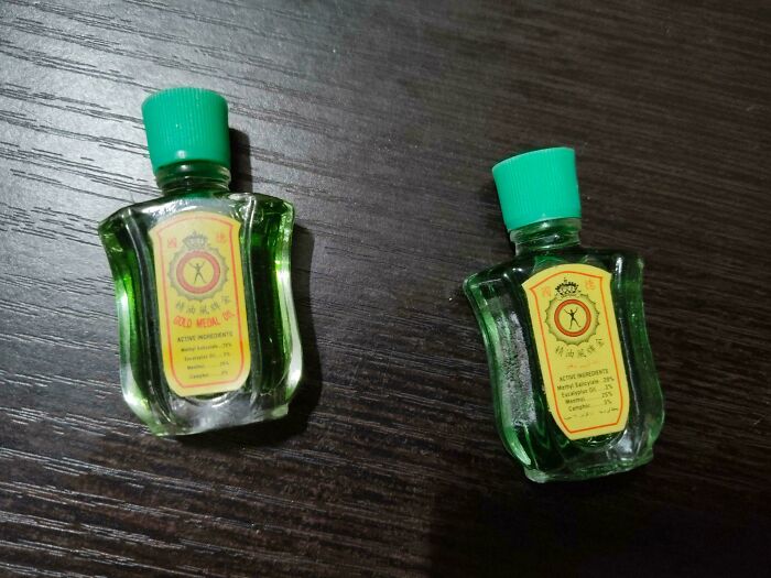 Two small green oil bottles with caps on a dark wooden table, photographed overhead, hinting at glitches in the matrix