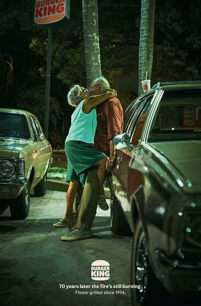 Couple kissing at night by cars in a humorous print advertisement showcasing creativity for Burger King brand.