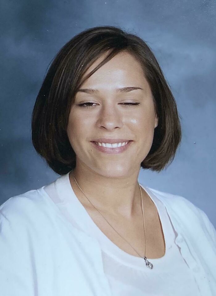 Woman with short brown bob smiling with one eye closed in a school portrait, woke up expecting surprise photo