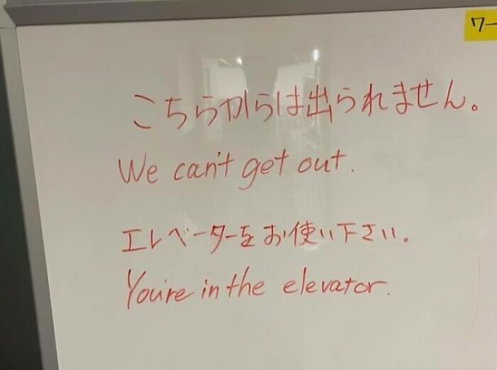Whiteboard with a funny English translation sign from Japan saying We can't get out and You're in the elevator, translation errors.
