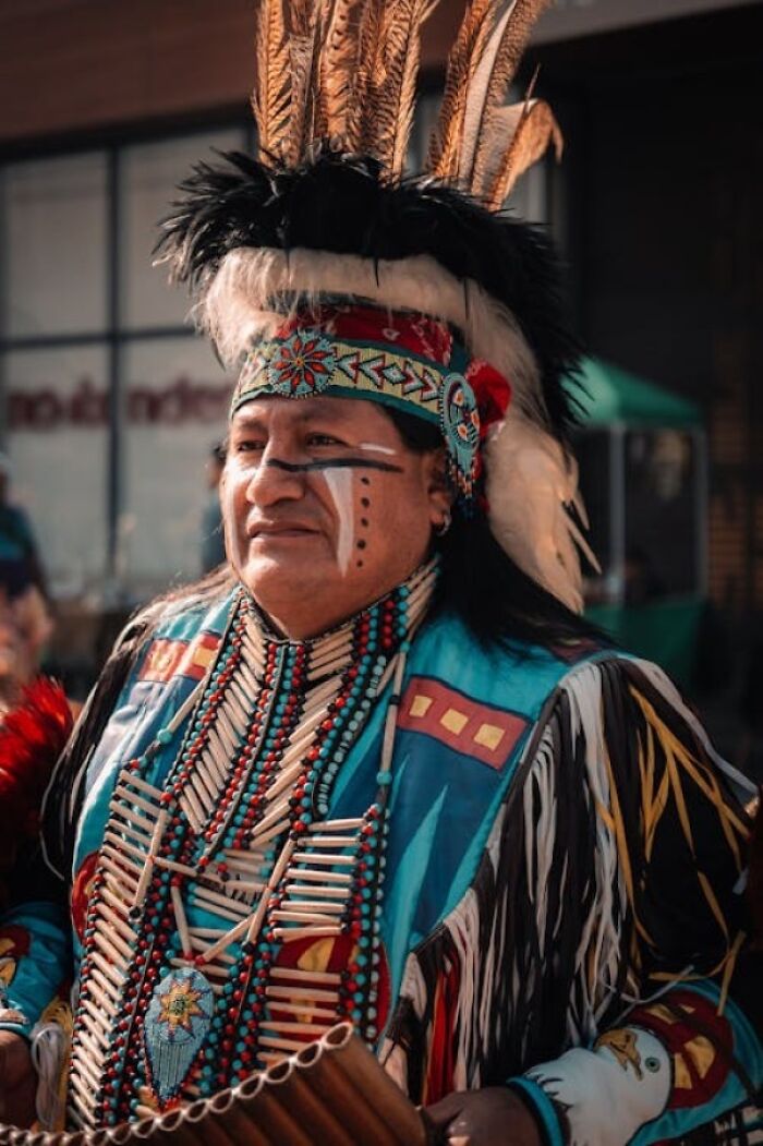 Native American man in traditional regalia adorned with feathers and beads, reflecting rich family secrets and heritage.