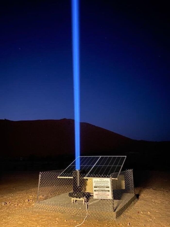 Amazing Photos solar-powered unit in desert at night emitting a bright vertical blue beam over fenced solar panels