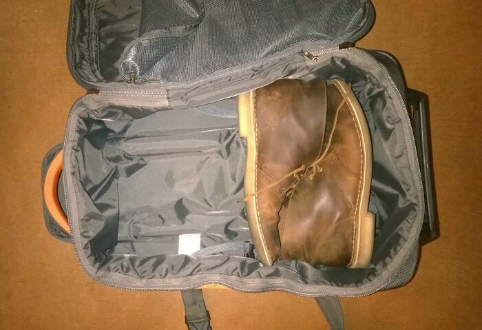 A large brown shoe inside an open black suitcase illustrating struggles only tall people face.