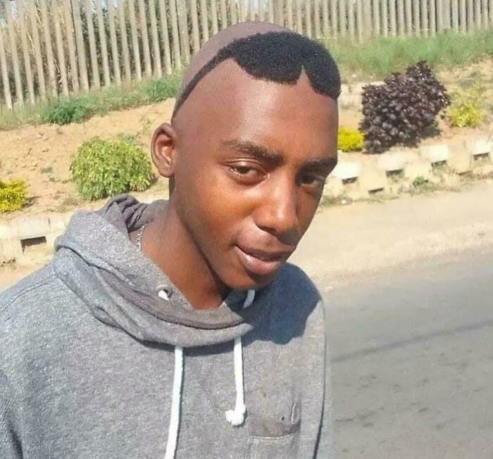 Young man with a confusing hairstyle that looks shaved partially, making it a funny and puzzling picture outdoors.