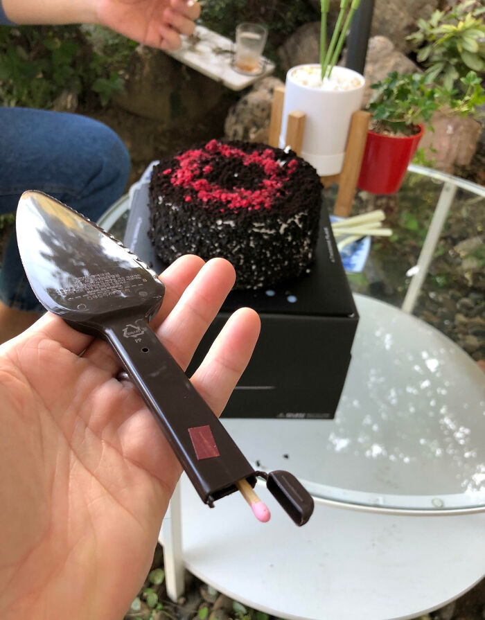 Hand holding a matchstick integrated into a cake server, showcasing impressive things countries implemented in creative tools.