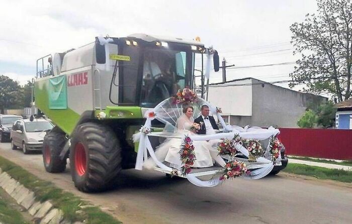 Bride and groom sitting on a decorated farm harvester in one of the most awkward wedding photos that will make you laugh and cringe.