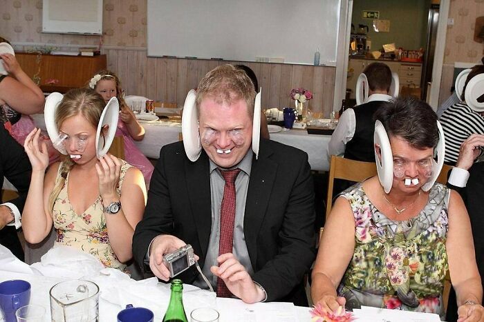 Three wedding guests wearing funny oversized ear props and fake teeth, creating awkward wedding photo moments.