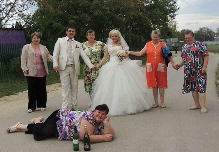 Group of people at a wedding with awkward poses including a bride and a woman lying on the road in awkward wedding photos.