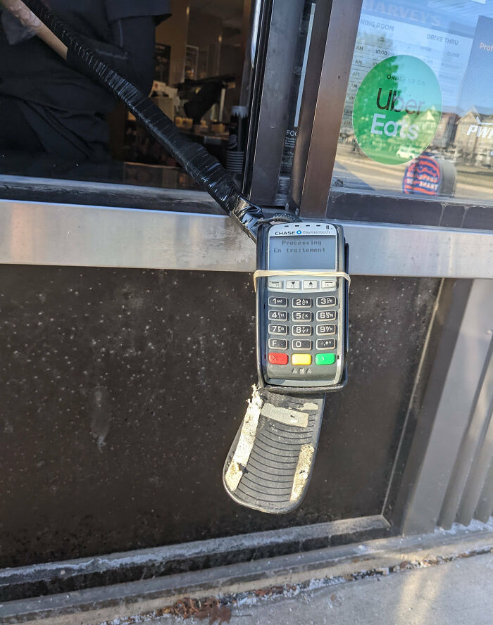 Contactless payment terminal attached to a drive-thru window, showcasing impressive technology implemented by countries.