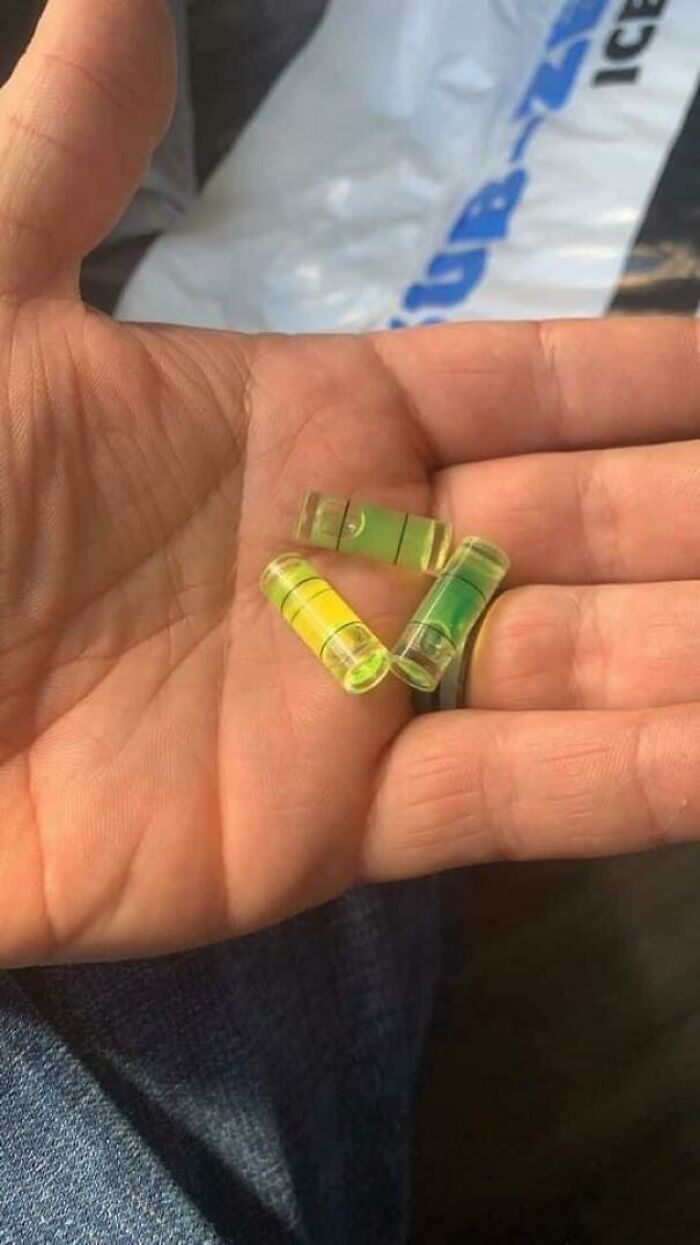 Three small bubble levels arranged in a triangle shape on a person's palm, a confusing picture that is funny.