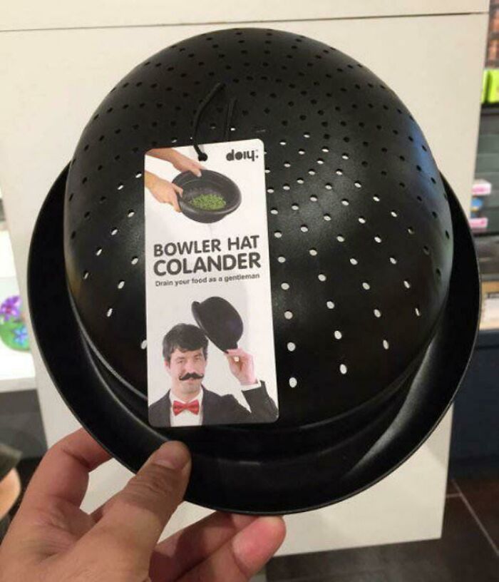 Hand holding a black bowler hat colander with holes, combining fashion with kitchen functionality in a confusing funny way.