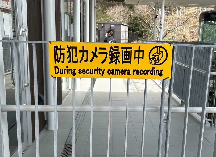 Yellow sign with a funny English translation about security camera recording in Japan, showing translation errors humorously.