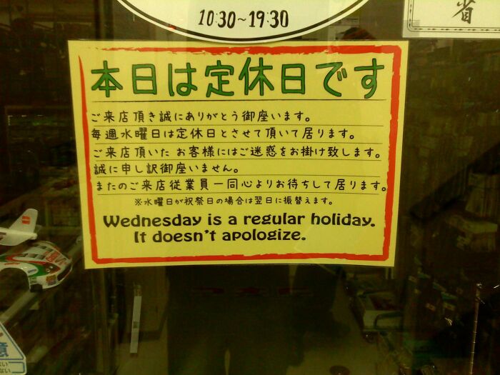 Sign with a humorous English translation error about Wednesday being a regular holiday that doesn’t apologize in Japan.