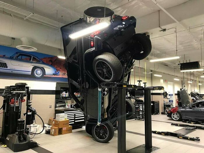 Car dangerously lifted and flipped vertically in a garage showing an unfortunate and expensive fail.