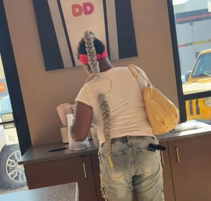 Woman with a long, braided hairstyle at a counter, showcasing one of the most disastrous hairstyles.