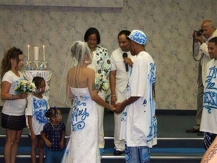 Bride wearing a wedding dress with questionable taste featuring spray-painted graffiti, standing with groom in matching casual streetwear.