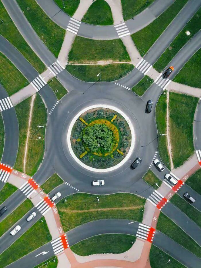 Aerial view of a roundabout showing desire paths where people walk outside planned sidewalks in urban design.