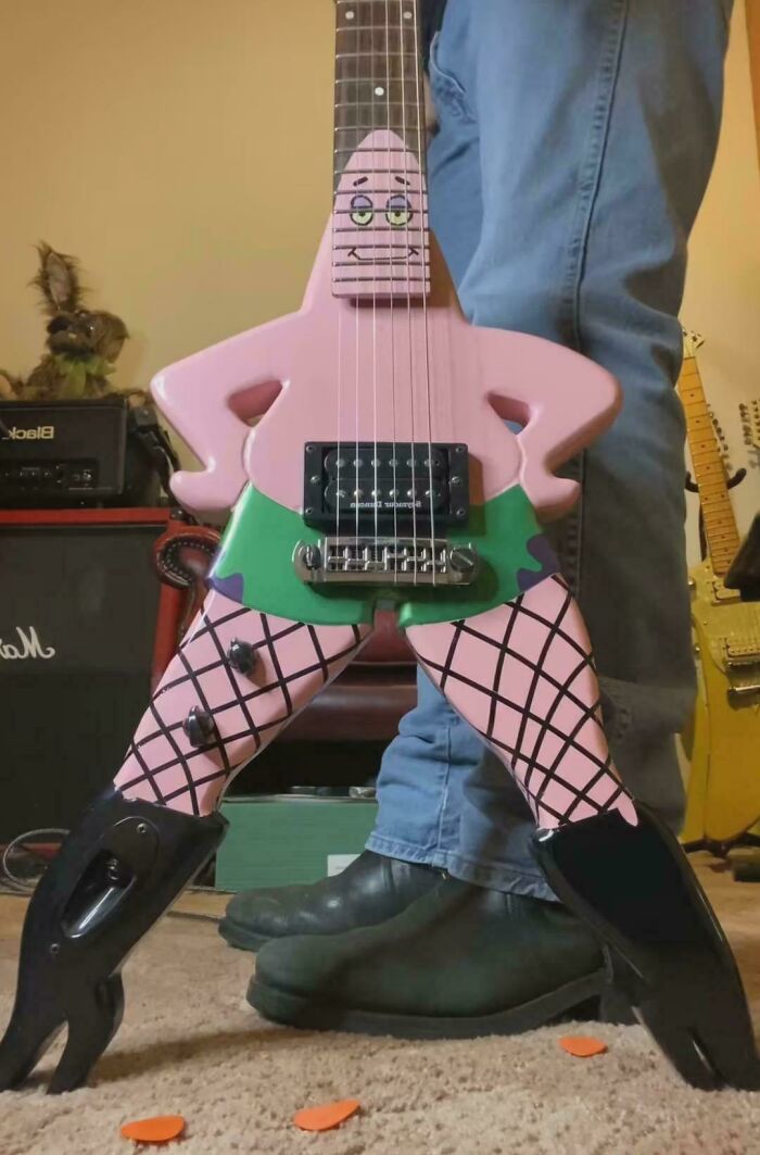 Pink Patrick Star guitar with fishnet stockings and boots standing next to a person wearing jeans and boots in a music room.