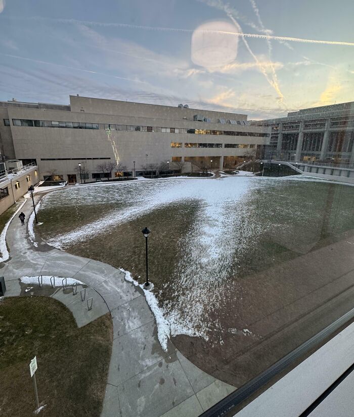 Desire paths visible in snow and grass showing how people walk versus city sidewalk planning in an urban courtyard.