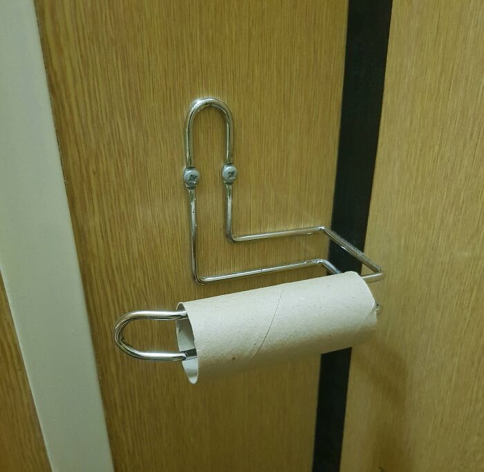 Empty toilet paper roll on a holder shaped like a confused face, creating a funny and confusing picture.