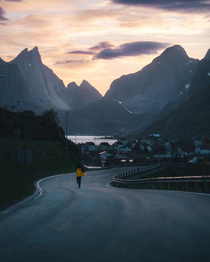 Person walking on a curved road in a mountain village at dusk, illustrating peaceful countries that sleep the most.