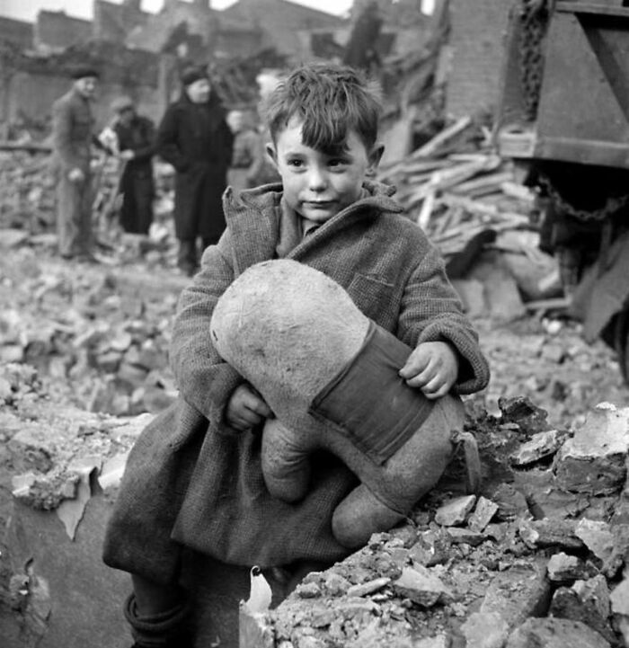 Young boy clinging to a stuffed toy amid rubble, a powerful photograph depicting the sad history of humanity.