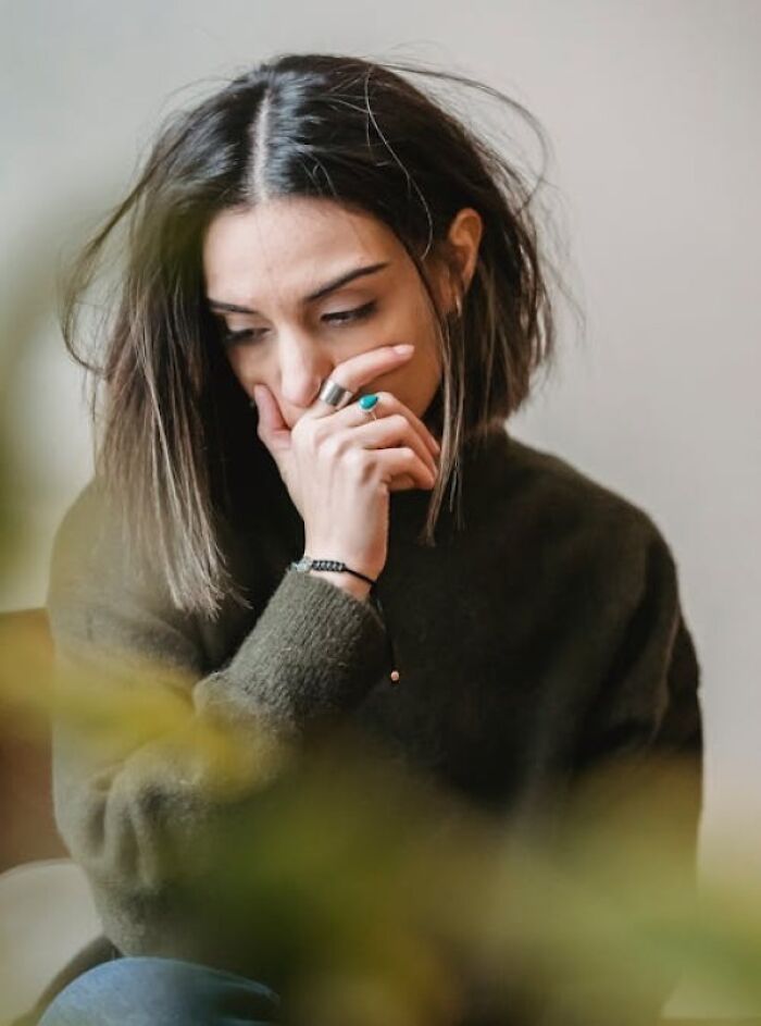 Woman in a dark sweater looking thoughtful and worried while reflecting on biggest family secrets and personal struggles.