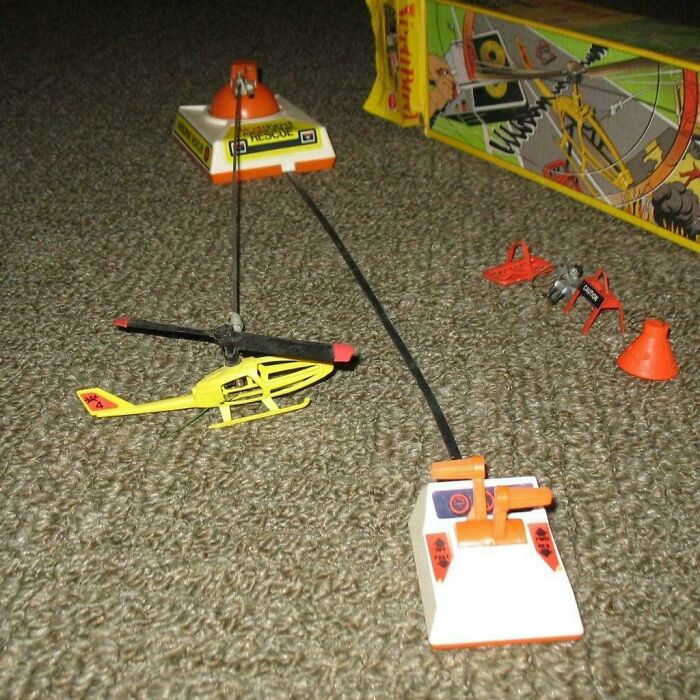 Vintage remote control toy helicopter with controller and accessories on carpet, nostalgic item to make you feel old.