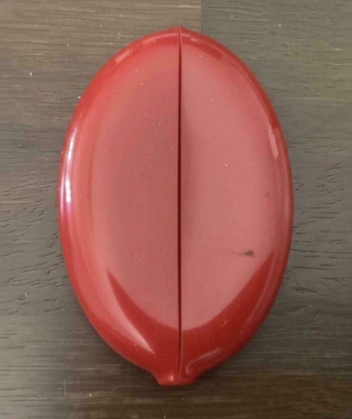 Vintage red plastic lemon squeezer on a wooden surface, a nostalgic item to make you feel old as heck.