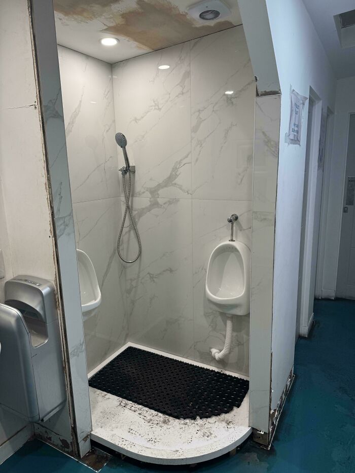 Bathroom design fail showing urinals inside a shower area creating awkward and impractical problems for users and space.