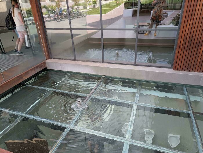 Glass floor with water beneath causing a slipping hazard, showing a clear example of designers making dumb decisions.